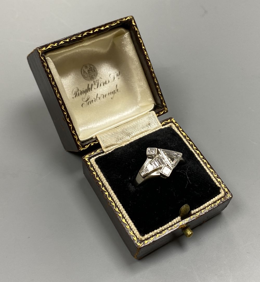 An unusual white metal (stamped Plat), triangular, square and graduated baguette cut diamond cluster set dress ring,